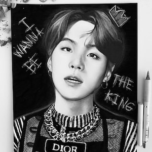 May include: Black and white drawing of a person with a crown above their head. The person is wearing a black and white striped shirt with a silver chain necklace and a black patch that says "DIOR". The text "BE I WANNA THE KING" is written on the left side of the image.