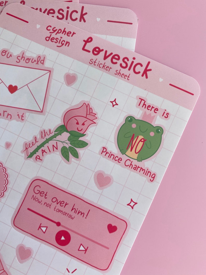 May include: A pink sticker sheet with a grid pattern. The sheet includes stickers with various designs, including a rose with a face, a frog with a crown, and a music player with the text "Get over him! Now, not tomorrow". The sheet also includes the text "Lovesick sticker sheet" and "There is no Prince Charming".