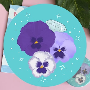 May include: A turquoise blue background with three purple and white pansies and a single diamond ring. The pansies are arranged in a cluster with the diamond ring on top.