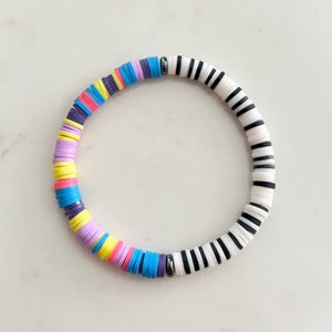May include: A colorful bracelet with black and white striped beads and a mix of purple, pink, yellow, and blue beads.