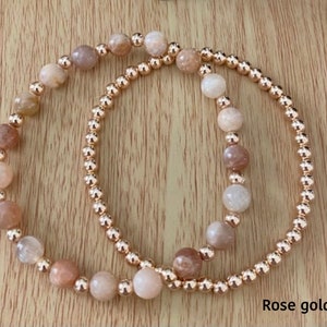 May include: Two bracelets with rose gold beads and sunstone beads. The bracelets are stacked on top of each other. The text "Rose gold set" is visible in the bottom right corner of the image.