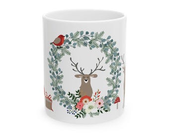 May include: White ceramic mug featuring a festive design. The design includes a deer with antlers, a wreath of greenery, a red bird, and colorful flowers. A gift box and a mushroom are also included in the design. This mug is perfect for enjoying hot beverages.