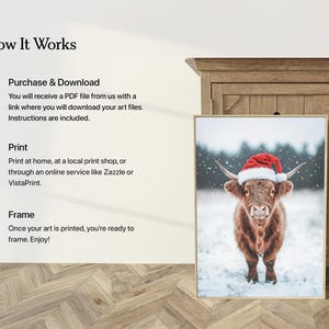 May include: A framed print featuring a Highland cow wearing a Santa hat, set against a snowy backdrop. The artwork is displayed next to a wooden cabinet. The text on the left side of the image reads "How It Works".