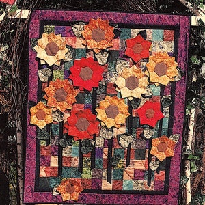 Puede incluir: Una colcha colorida con un diseño de patchwork que presenta una variedad de telas en tonos de rojo, naranja, amarillo, verde, azul y morado. La colcha está decorada con múltiples girasoles aplicados en varios tonos de marrón, naranja y rojo.