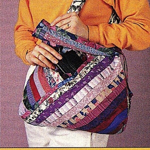 May include: A patchwork tote bag with a variety of colors and patterns, including pink, purple, blue, and red. The bag is made of fabric scraps sewn together in a striped pattern. The bag is being held by a person wearing a bright orange sweater.