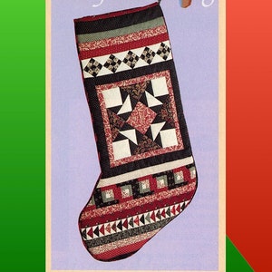 Może przedstawiać: Świąteczna pończoszka pikowana w kolorze czerwonym, czarnym, białym i złotym. Pończoszka jest ozdobiona różnymi wzorami, w tym diamentami, gwiazdami i wzorami kwiatowymi. Pończoszka wisi na drewnianym pręcie z napisem "Toby's Stocking" nad nią.