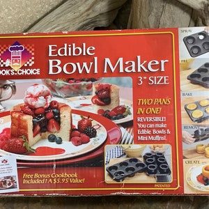 Könnte beinhalten: Eine rote Box mit einem weiß-schwarzen Logo, auf dem "Cook's Choice" steht, und den Worten "Edible Bowl Maker" in großen weißen Buchstaben. Die Box zeigt eine Größe von 7,6 cm, zwei Formen in einem und ein kostenloses Bonus-Kochbuch. Die Box zeigt auch Bilder des Produkts, das verwendet wird, um essbare Schalen und Mini-Muffins zu machen.