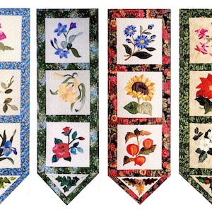 Könnte beinhalten: Vier Stoffwandbehänge mit Patchwork-Design, die verschiedene Blumen zeigen. Jeder Behang hat drei Quadrate mit einem anderen Blumendesign in jedem Quadrat. Die Blumen umfassen Tulpen, Gänseblümchen, Iris, Lilien, Sonnenblumen, Stockrosen und Weihnachtssterne.