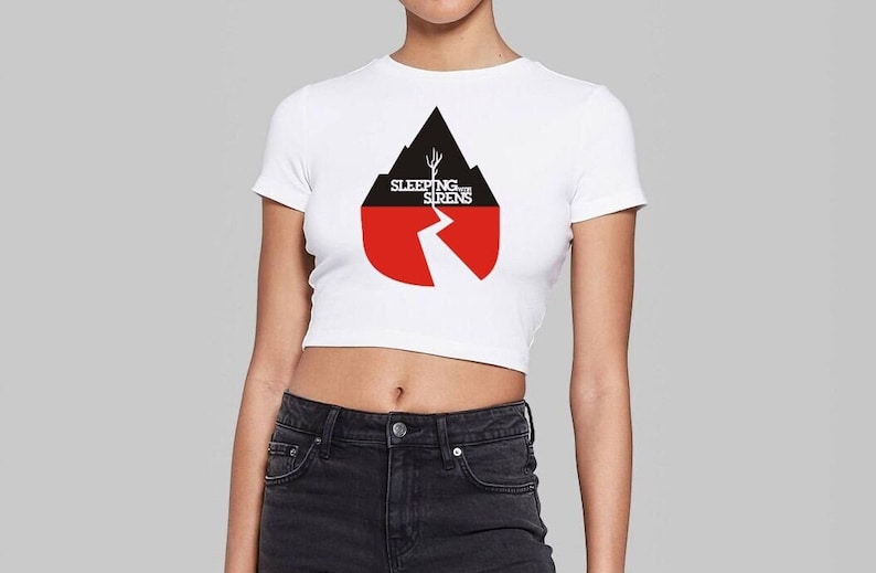 Puede incluir: Top corto blanco con un dise&ntilde;o gr&aacute;fico. El dise&ntilde;o presenta una forma de monta&ntilde;a negra, una secci&oacute;n inferior roja y el texto "SLEEPING WITH SIRENS" en blanco. La parte superior se usa con jeans de mezclilla negros.