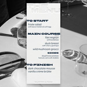 May include: A black and white image of a restaurant table setting. A menu lists dishes like filet mignon and duck breast. The table is set with plates, silverware, and glasses.