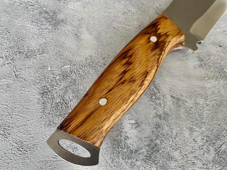 K&ouml;nnte beinhalten: Ein Messer mit einem Holzgriff und einer Klinge aus Edelstahl. Der Griff ist aus dunklem Holz mit einer hellbraunen Maserung. Am Griff befinden sich zwei silberne Nieten.