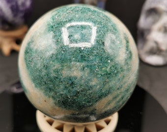May include: A green and white marble sphere on a white stand. The sphere has a swirling pattern of green and white.