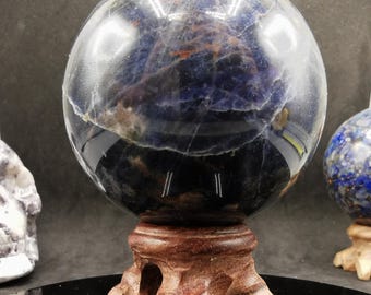 May include: A polished blue and white crystal ball on a wooden stand. The ball is translucent and has a swirling pattern of blue and white.