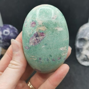 Könnte beinhalten: Ein polierter, eiförmiger Stein in Grün und Pink mit einer glatten Oberfläche und rosa und weißen Einschlüssen.