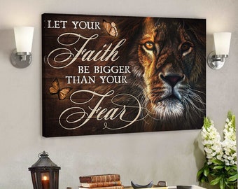 Puede incluir: Una impresión de lienzo motivacional con la cara de un león y las palabras "Deja que tu fe sea más grande que tu miedo" en una fuente decorativa. El fondo es un patrón de veta de madera con dos mariposas.