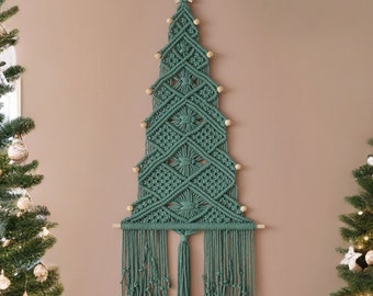 May include: A wall hanging made of dark green macrame cord shaped like a Christmas tree. The design features intricate knotted patterns, small wooden beads along the edges, a wooden star at the top, and a long fringe at the bottom.