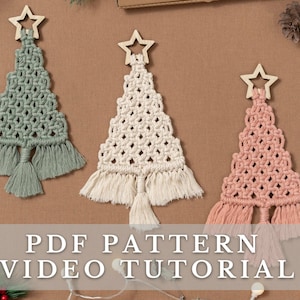 May include: Three macrame Christmas tree ornaments in green, white, and pink. Each ornament has a wooden star at the top and a fringe at the bottom. The ornaments are displayed on a brown surface. PDF PATTERN VIDEO TUTORIAL.