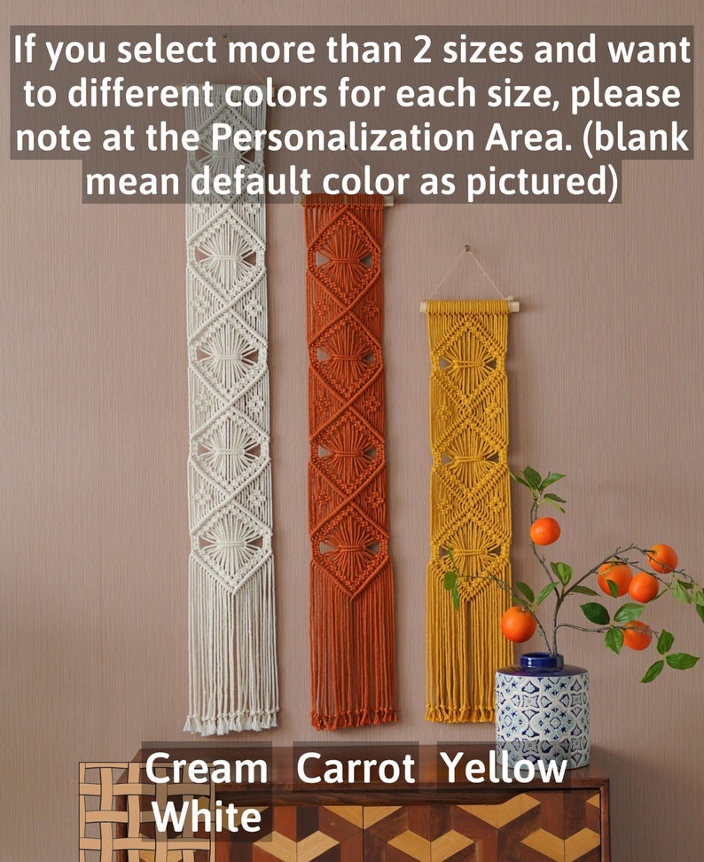 May include: Three macrame wall hangings in cream, orange, and yellow. The hangings are made with a diamond pattern and have fringe at the bottom. The text "Cream", "Carrot", and "Yellow" is written below the hangings.