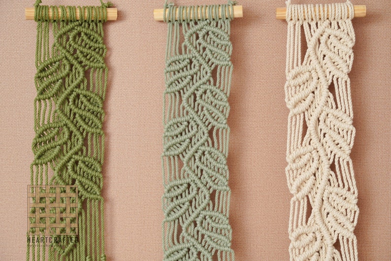 May include: Three macrame wall hangings with a leaf pattern. The hangings are made with natural cotton cord and are in shades of green and cream.