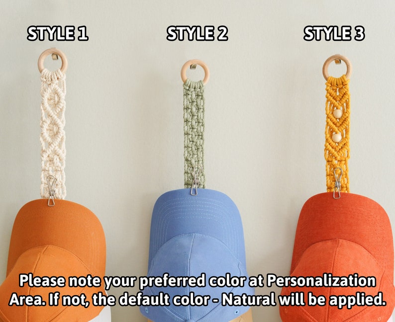 May include: Macrame hat hangers in three styles, each with a wooden ring and clip. Style 1 is cream, Style 2 is green, and Style 3 is yellow. The hangers are holding baseball caps in orange and blue. Text on the image: Please note your preferred color at Personalization Area.