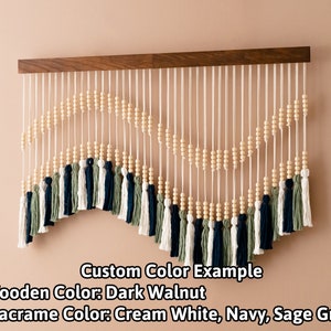 May include: A macrame wall hanging with a wooden dowel, cream white, navy, and sage green yarn, and wooden beads. Custom Color Example + Wooden Color: Dark Walnut + Macrame Color: Cream White, Navy, Sage Green