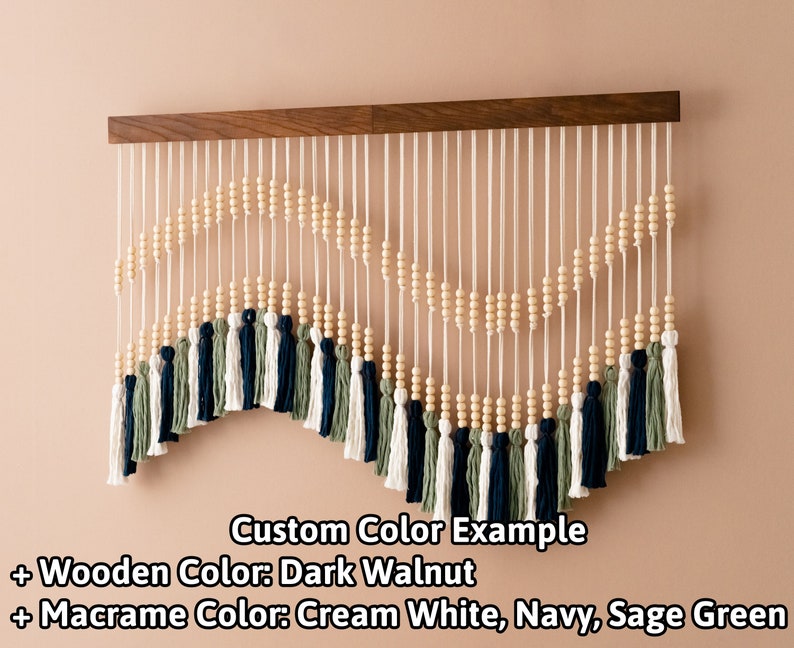 May include: A macrame wall hanging with a wooden dowel, cream white, navy, and sage green yarn, and wooden beads. Custom Color Example + Wooden Color: Dark Walnut + Macrame Color: Cream White, Navy, Sage Green