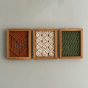 Pu&ograve; includere: Tre arazzi da parete in macram&egrave; incorniciati. Le cornici in legno racchiudono opere d'arte in macram&egrave; nei colori ruggine, crema e verde. I motivi macram&egrave; sono geometrici e strutturati. Decorazione murale.