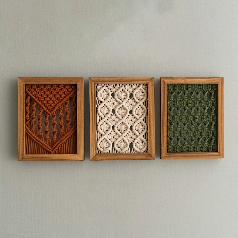 Pu&ograve; includere: Tre arazzi da parete in macram&egrave; incorniciati. Le cornici in legno racchiudono opere d'arte in macram&egrave; nei colori ruggine, crema e verde. I motivi macram&egrave; sono geometrici e strutturati. Decorazione murale.