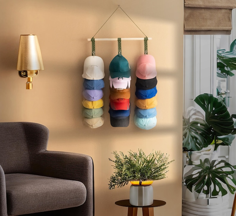 May include: A wall-mounted hat rack displaying a variety of baseball caps in different colors. The caps are stacked vertically, showcasing a range of hues from white and blue to red and black. The rack is suspended from a wooden bar.