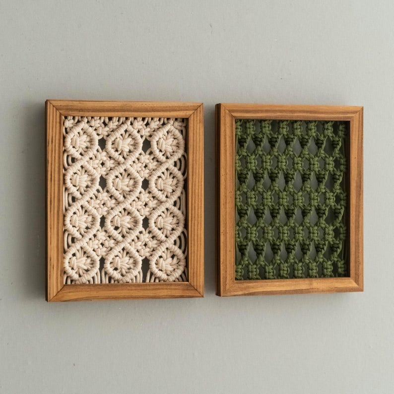 Pu&ograve; includere: Due arazzi da parete rettangolari in macram&egrave; in cornici di legno. Uno presenta un motivo intrecciato color crema, l'altro un design intrecciato verde. Le cornici sono di colore marrone chiaro e lo sfondo &egrave; grigio chiaro.