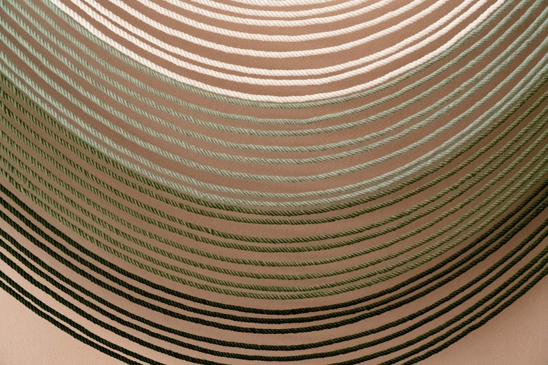 May include: A close-up of a wall with a gradient of green, white, and beige rope. The rope is arranged in a curved pattern, creating a visual effect of depth and texture.