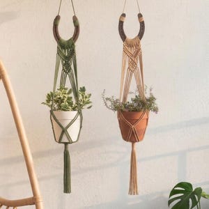 Könnte beinhalten: Ein Set aus drei Keramikbechern mit gesprenkelter, matter Oberfläche. Die Becher sind in Creme-, Hellgrau- und Dunkelgrautönen gehalten. Jeder Becher hat ein schlichtes, minimalistisches Design und einen abgerundeten Henkel.