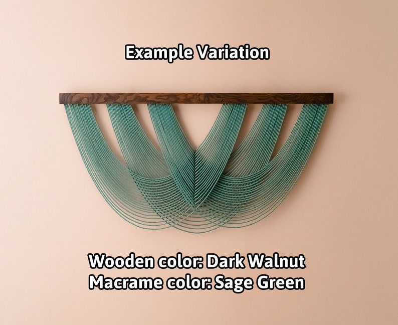 May include: A wall hanging featuring a dark walnut wooden bar with sage green macrame cords draped in a layered, scalloped pattern. The text "Example Variation", "Wooden color: Dark Walnut", and "Macrame color: Sage Green" is visible.