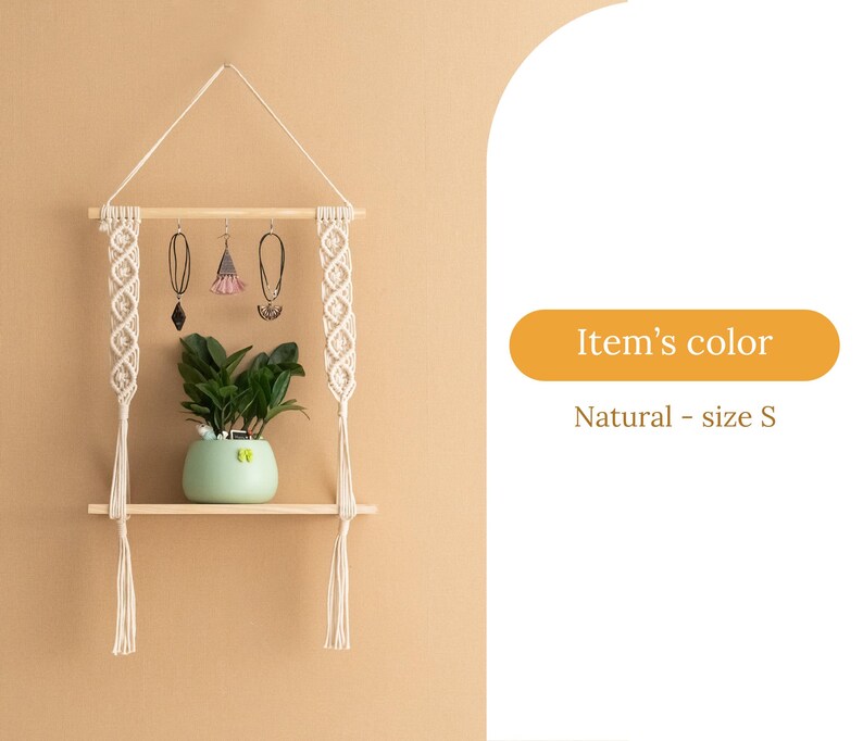 May include: A natural wood shelf with macrame hanging on each side. The shelf has a small potted plant on it and three earrings hanging from the macrame. The shelf is labelled "Item's colour: Natural - size S".