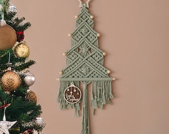 May include: A sage green macrame wall hanging shaped like a Christmas tree, featuring a wooden star at the top, small wooden beads, and a round wooden ornament engraved with the text Andy & Sophia hanging from a horizontal dowel.