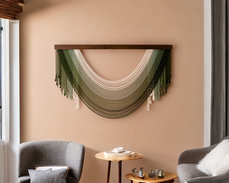 May include: A wall hanging made of woven yarn in shades of green and cream. The yarn is arranged in a curved shape, creating a modern and minimalist design.