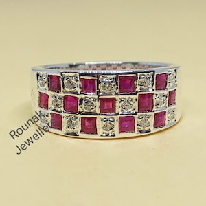 Può includere: Un anello a fascia d'argento con tre file di pietre preziose rosse quadrate e pietre preziose bianche più piccole.