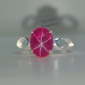 Peut inclure: Bague en argent avec une superbe pierre de rubis étoilé rose. Le rubis ovale présente un motif en étoile à six rayons. La bague a un design minimaliste avec une finition polie, mettant en valeur la beauté de la pierre.
