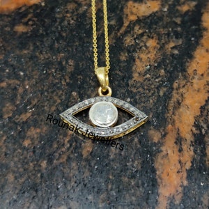 May include: A gold chain necklace with a silver evil eye pendant set with small diamonds. The pendant is in the shape of an eye with a round center stone.