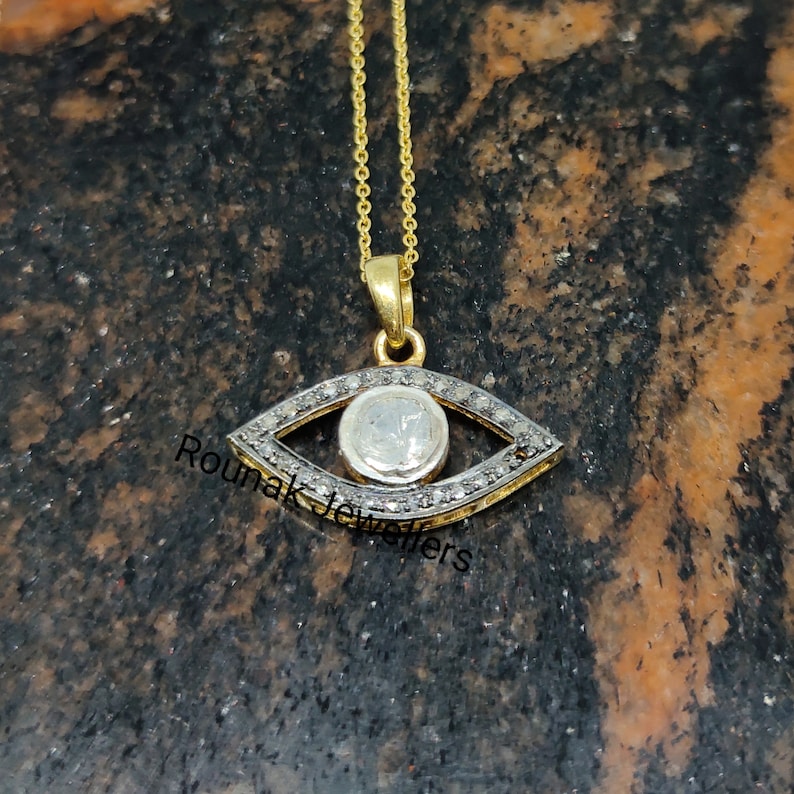 May include: A gold chain necklace with a silver evil eye pendant set with small diamonds. The pendant is in the shape of an eye with a round center stone.