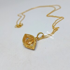 May include: A gold pendant necklace with a detailed design featuring a heart shape inside a larger eye shape. The necklace is on a white background with the text "Rounak Jewellers" visible.