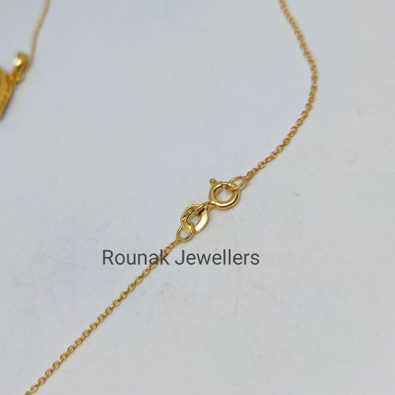 May include: A gold chain necklace with a lobster clasp closure. The chain is a delicate, fine link style. The text "Rounak Jewellers" is visible in the image.