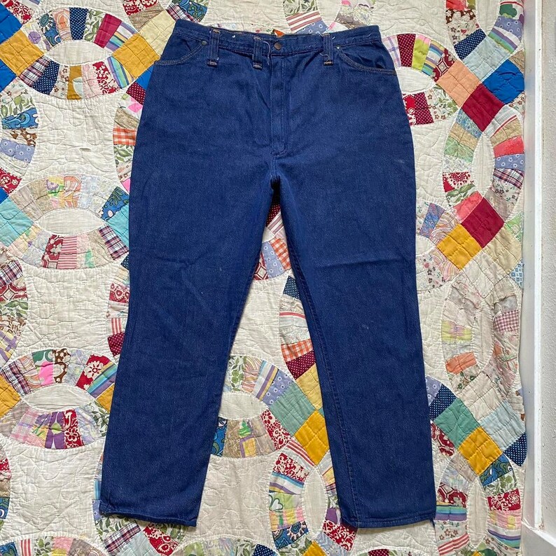 Puede incluir: Un par de pantalones vaqueros de mezclilla azul oscuro con cintura alta y piernas rectas.