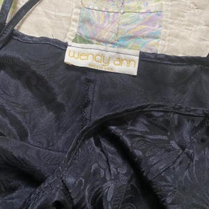 May include: A black satin slip dress with a floral pattern. The dress has adjustable straps and a label that reads "Wendy Ann Made in USA."
