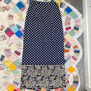 May include: A long navy blue skirt with white polka dots and a paisley print border. The skirt is made of a soft, flowing fabric.