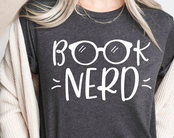 May include: A dark gray t-shirt with the text "BOOK NERD" in white lettering. The text is accompanied by a pair of white glasses.