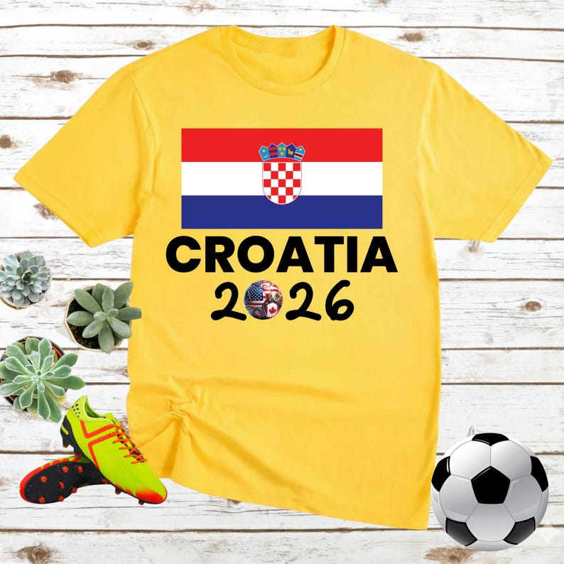 May include: A yellow t-shirt with the Croatian flag and the text "CROATIA 2026". A soccer ball with flags of various countries is below the text. A football and football boots are also in the image.