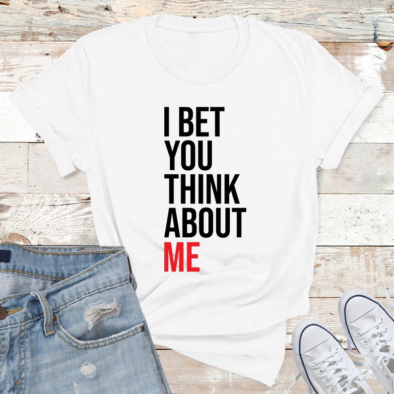 May include: White t-shirt with black text that reads "I bet you think about me". The word "me" is in red.