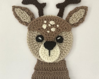 Puede incluir: Una cabeza de ciervo de crochet marrón con manchas blancas, cuernos marrones y ojos negros.