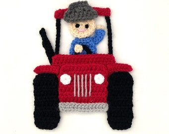 Puede incluir: Un tractor rojo de crochet con un volante negro y neumáticos negros. Una persona de crochet con un sombrero gris y una camisa azul conduce el tractor.